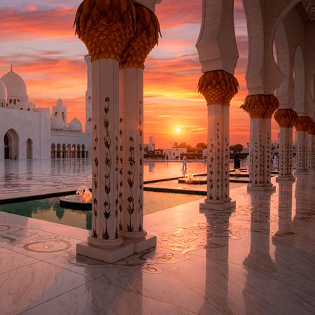 The stunning white marble courtyard of Sheikh Zayed Grand Mosque at sunset